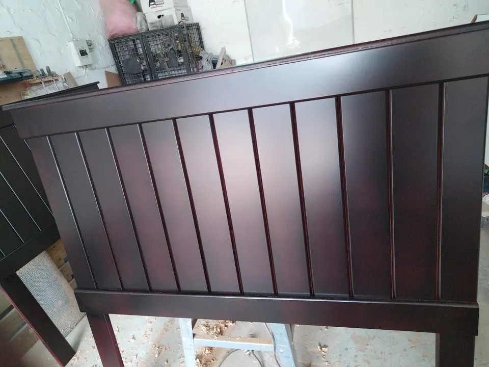 Dark wood panelled headboard with narrow vertical panels, a moulded top rail and legs that reach the floor