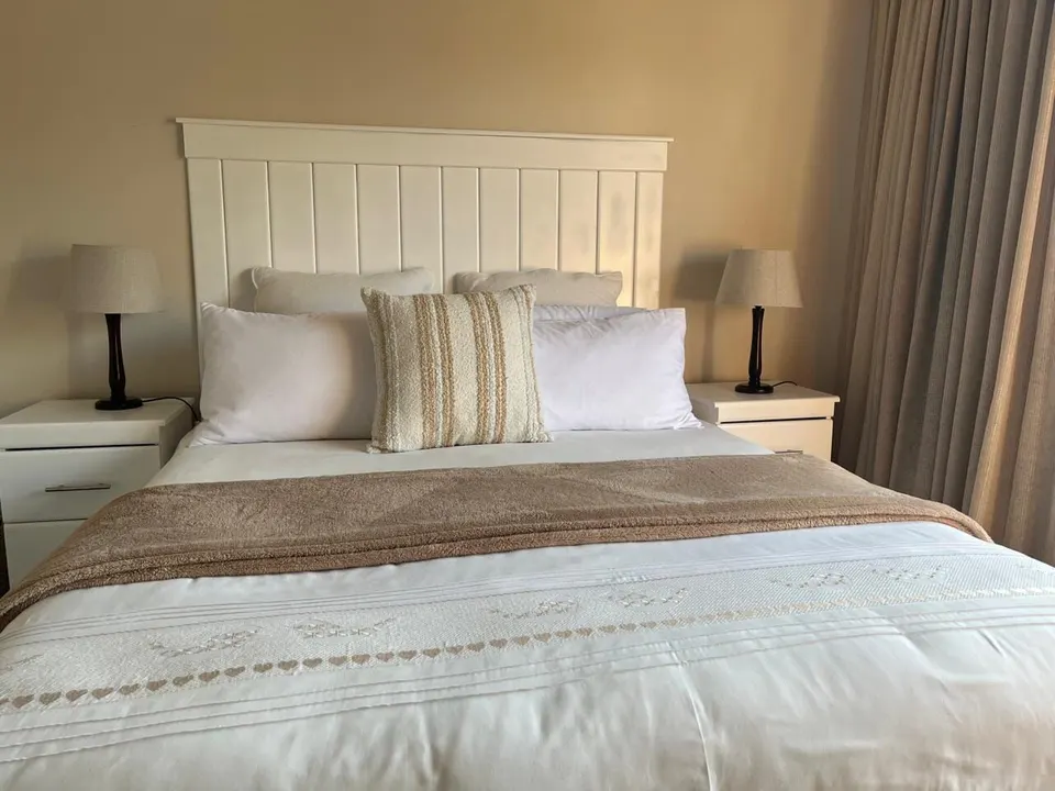 White panelled headboard on a made bed with two bedside pedestals