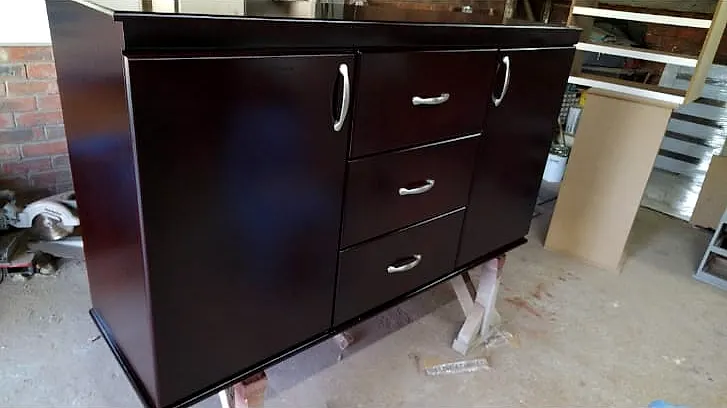 Dark wood sideboard with a cupboard door at each end and three drawers in the middle, with silver handles